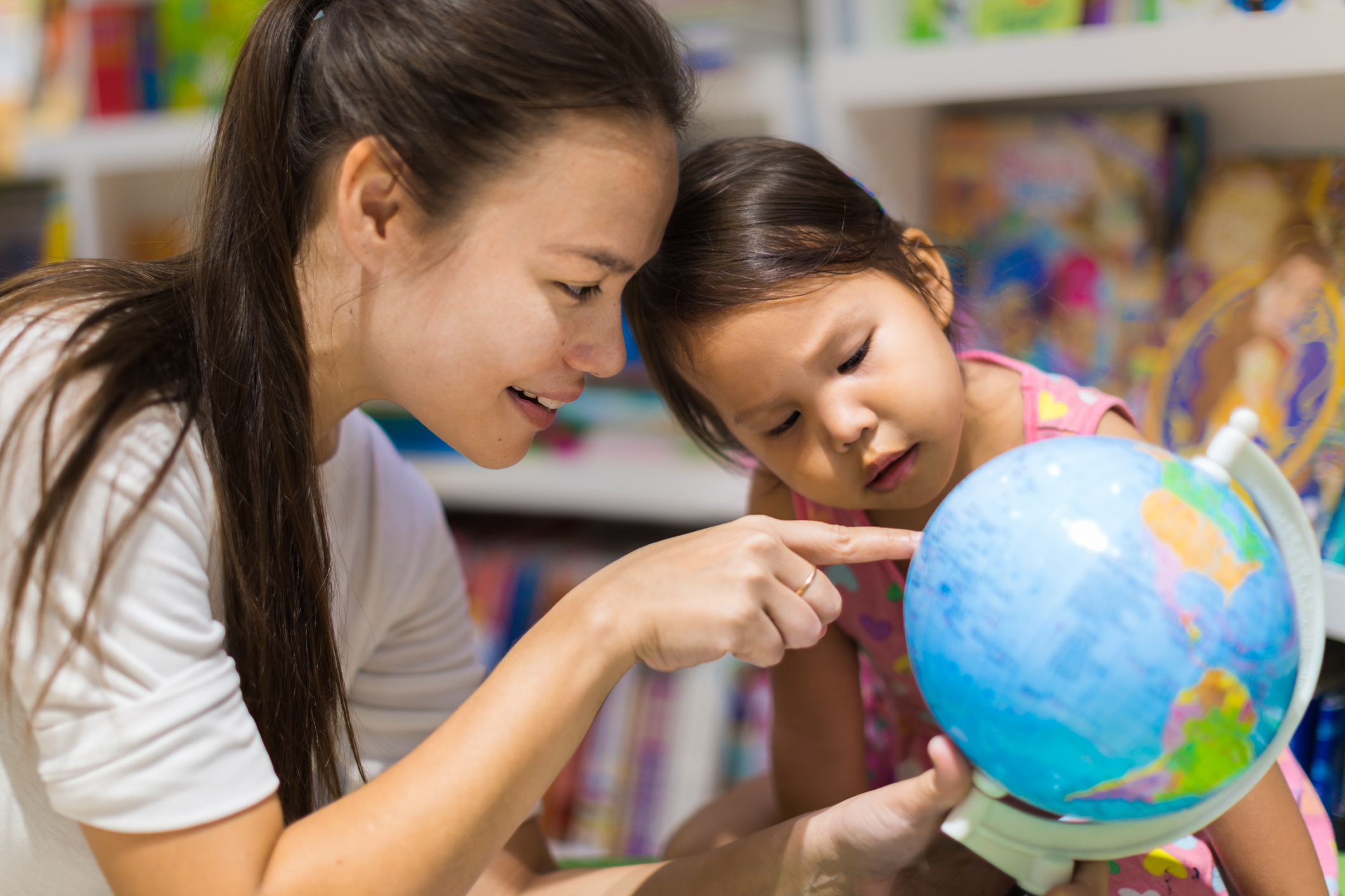 A teacher showing a young child a globe