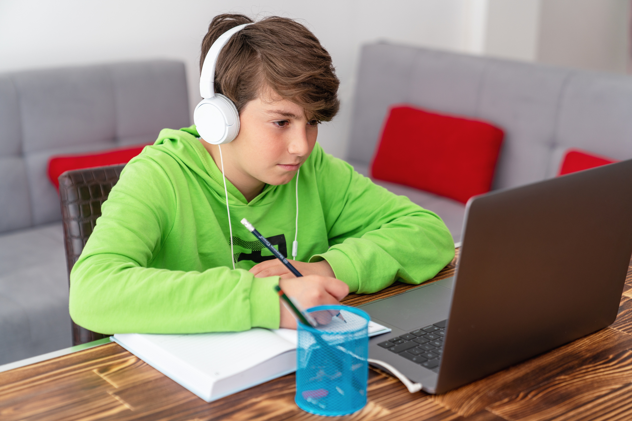 A young boy with headphones doing work.