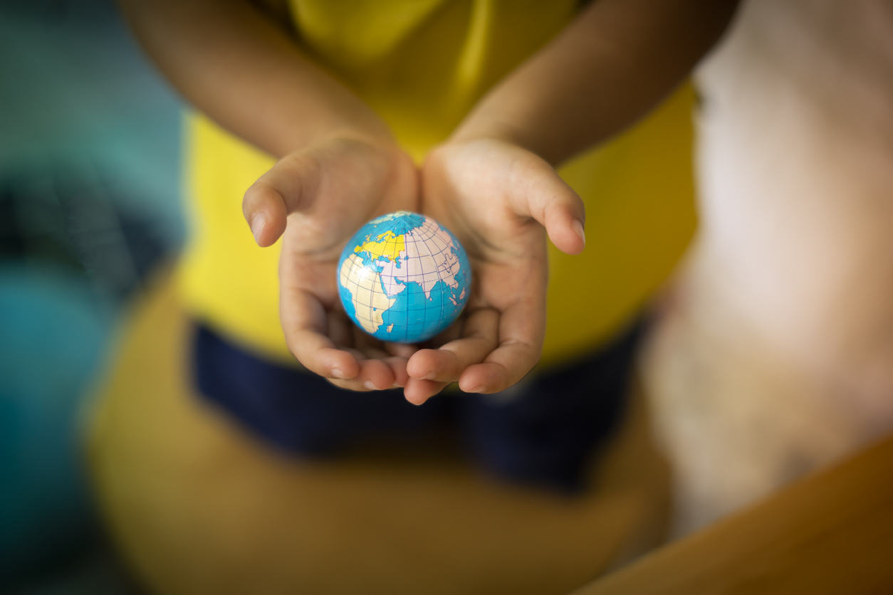 A child holding a globe, representing omeschooling around the world
