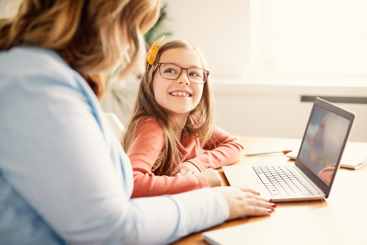 A tutor with a red haired child and laptop.