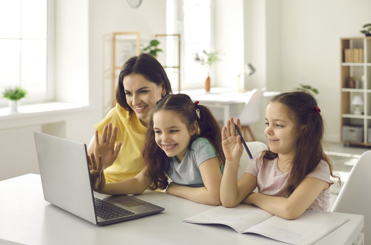 Children and a female adult gathered around a computer screen.